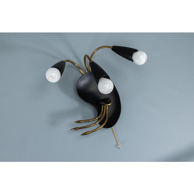 Italian Mid-Century Modern wall lamp in the style of Stilnovo, circa 1960. Sculptural three-light wall lamp combining...