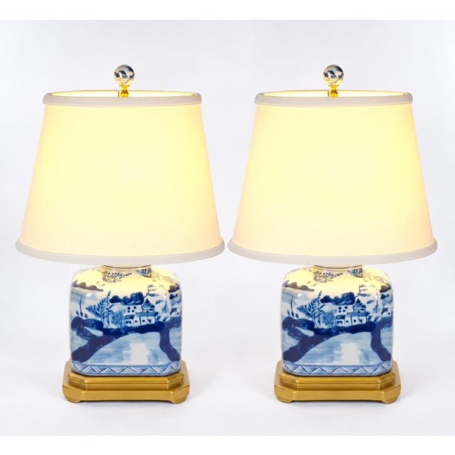This elegant pair of late 20th-century table lamps features glazed porcelain bodies decorated in a traditional blue and...