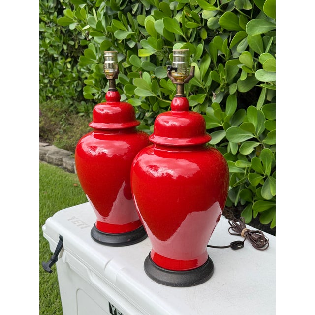 Striking vintage pair of ceramic table lamps featuring classic covered-jar forms finished in a vibrant glossy red crackle...