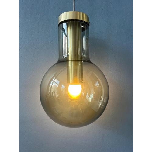 A rare Raak Maxi Globe pendant lamp from the 1970s, crafted in smoked glass with brass details. This iconic Dutch Design...