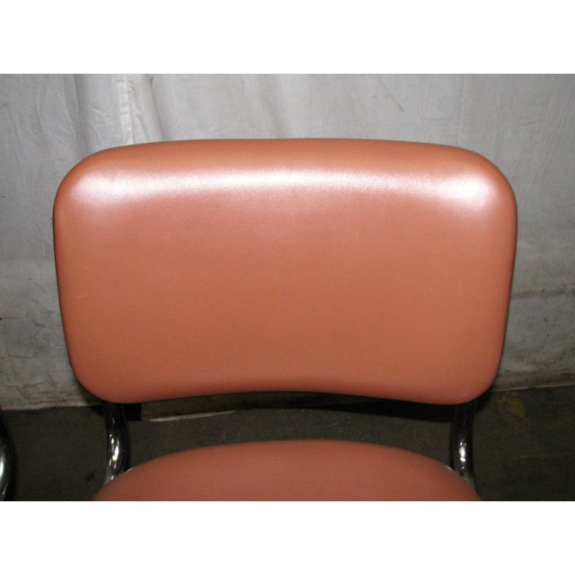 Mid Century Modern cantilevered chair with a tubular chrome plated steel frame and salmon colored vinyl upholstery....
