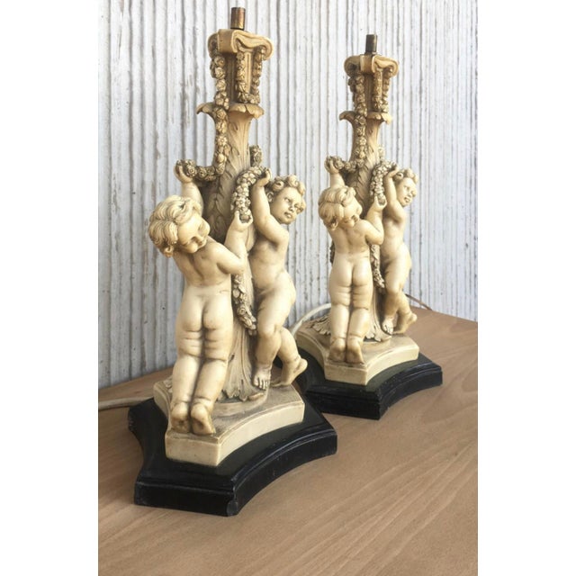 These lamps have a white cream glazed finish that covers this pair of resin cherubs from Italy in the early 20th century....