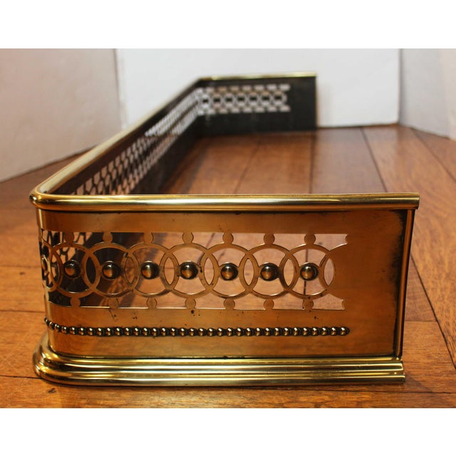 Circa 1870s pierced brass fireplace fender, English. A handsome form with motif of interlaced circles accented with...