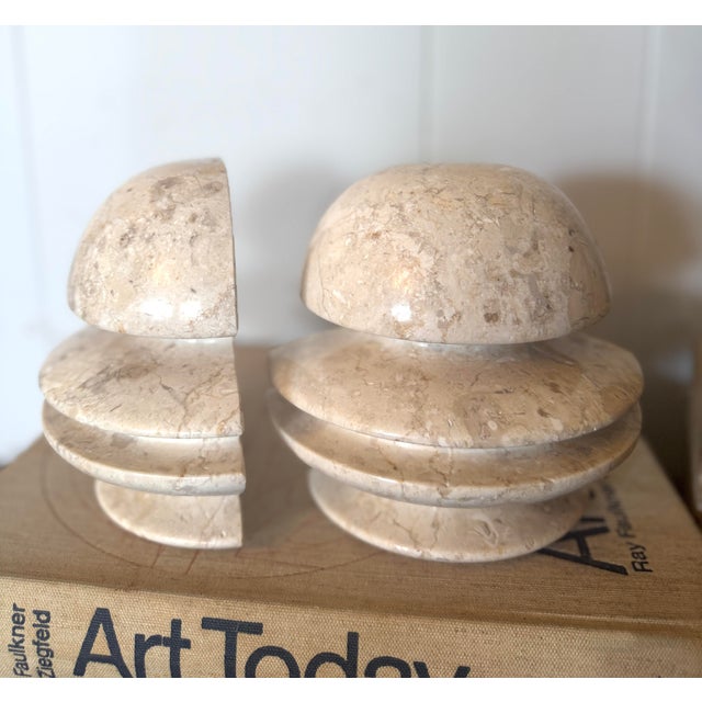 A striking pair of vintage travertine sculptural bookends featuring a bold layered architectural form carved from solid...