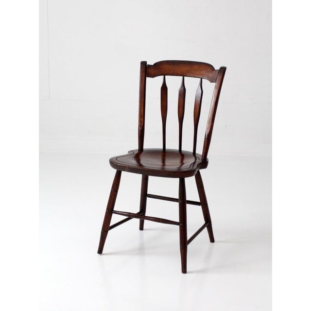 A vintage Windsor style side chair featuring a sculpted seat, spindle back, tapered turned legs, and softly arched crest...