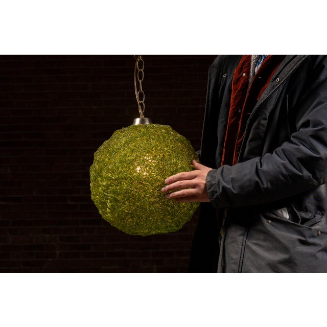 Striking mid-century pendant light featuring a spherical shade formed from intertwined translucent acrylic strands in a...