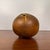 Sphere-shaped bud vase on three little feet. Bud vase has various sized holes along the top with dripped glaze detailing...