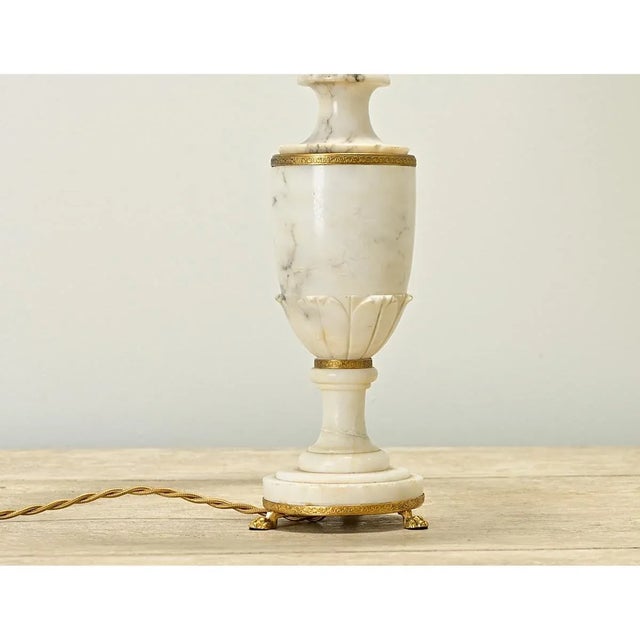 An Italian Empire-style carved marble and brass table lamp. This Neoclassical lamp is shaped like an urn (or trophy) with...
