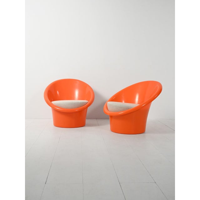 A pair of "Skopa" chairs from 1974, featuring a rigid orange plastic shell, a conical base, and cushions upholstered in...