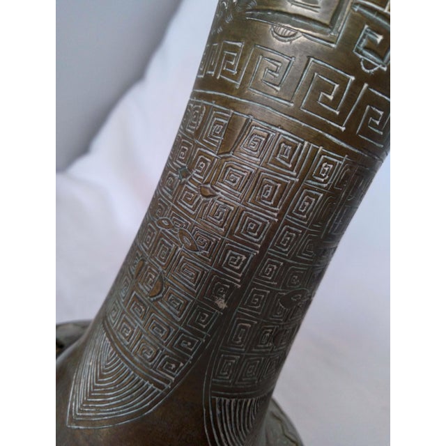 This is a striking bronze or brass double-handled vase featuring classic archaic-style motifs, including geometric key...