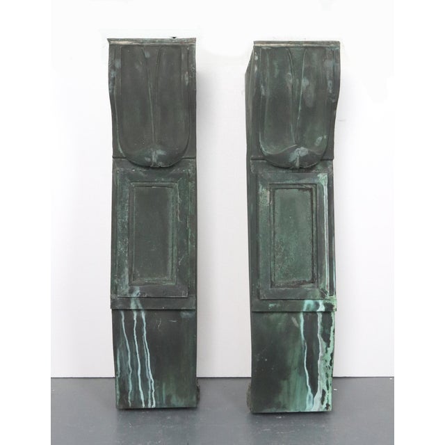 Reclaimed antique corbels with a formal symmetry and classical details, such as a curved top section and a rectangular...