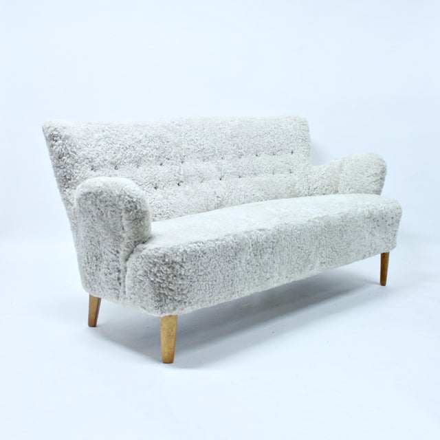 Rare Swedish Modern sofa in sheep skin, 1940s. Superb rounded shaped armrests. New off-white sheepskin upholstery with...