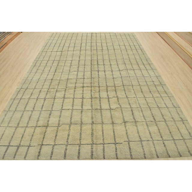 A contemporary Moroccan rug hand-knotted with an all-wool pile on a cotton foundation. This plush area rug features an...