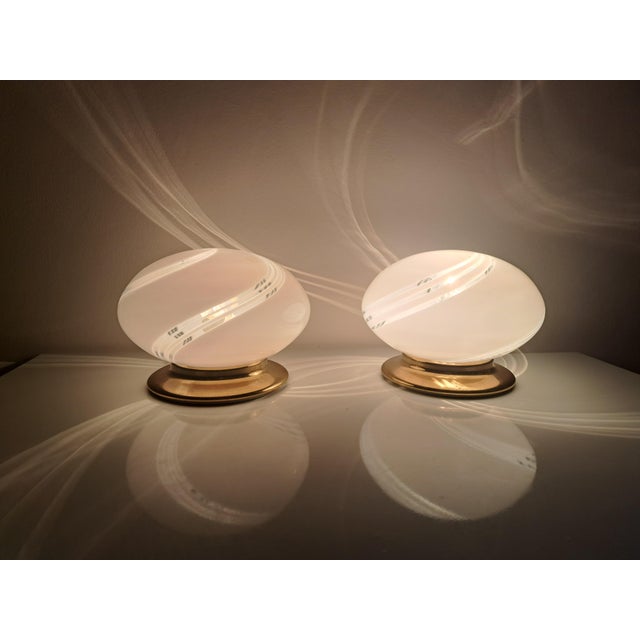 Pair of vintage 1970s table lamps in white murano glass with a spiral design and a gold-colored brass base. the pair of...