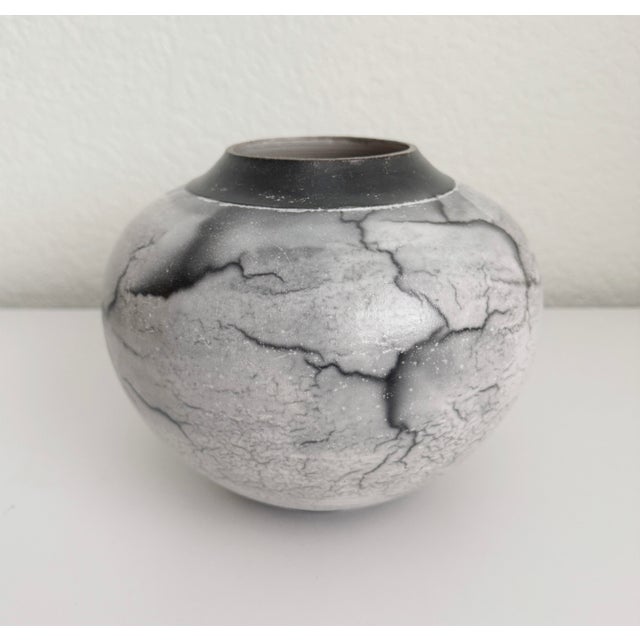 Stunning ceramic, raku vase featuring white/taupe glaze and heavy black crazing. Artist signed. This type of raku features...