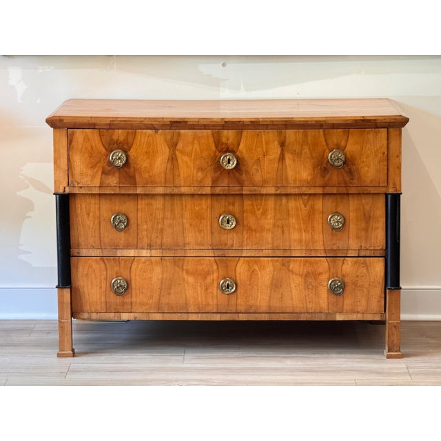 A Biedermeier cherry wood commode, circa 1825, possibly from Vienna, with a molded top over three long drawers faced in...