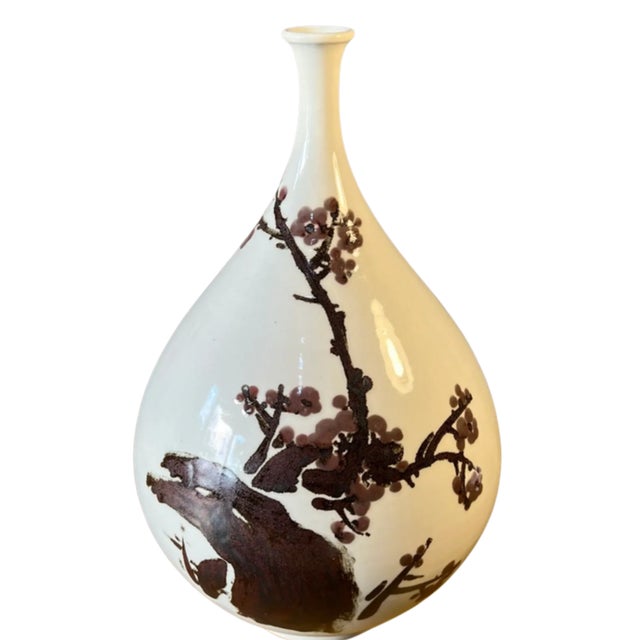This large vintage white porcelain bottle vase was made in Japan, and showcases a classic East Asian aesthetic, defined by...