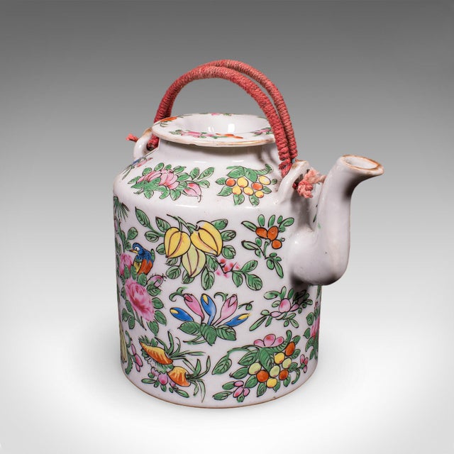This is a small antique decorative teapot. An Oriental, ceramic Chá pot with padded wicker case, dating to the early 20th...