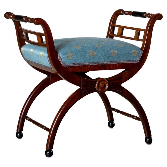 Small 19th Century tabouret on an x-shaped frame with turned armrests and ball feet. The stool is upholstered in a light...
