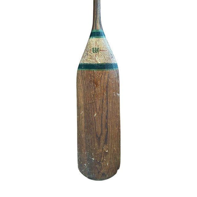 A charming, early 20th century canoe paddle. Features a solid wood construction with hand painted striping in shades of...