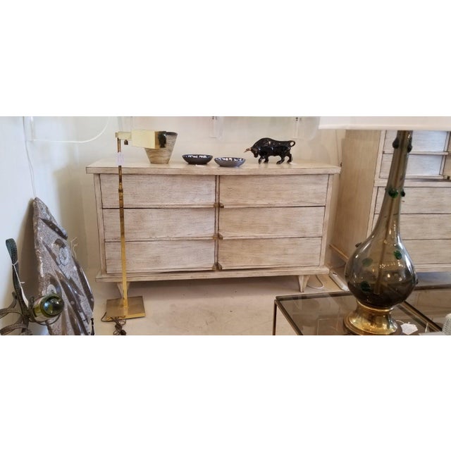 Dims.: 58"W x 19.75"D x 33.5"H Finish: White Wash with brass accents Mid Century six-drawer dresser with brass accents....
