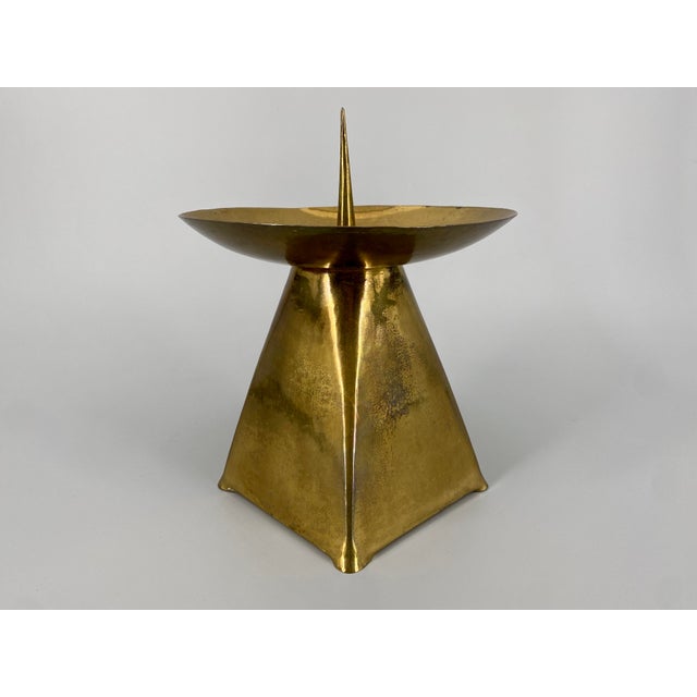 A candle holder * Made of brass * with an engraved Madonna and Child motif * Pyramidal base * Wide, round drip tray for...