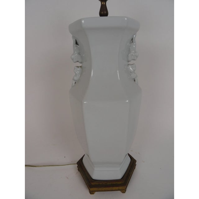 Elegant blanc de chin six-sided lamp on six-sided custom gold leaf base with dog handles.