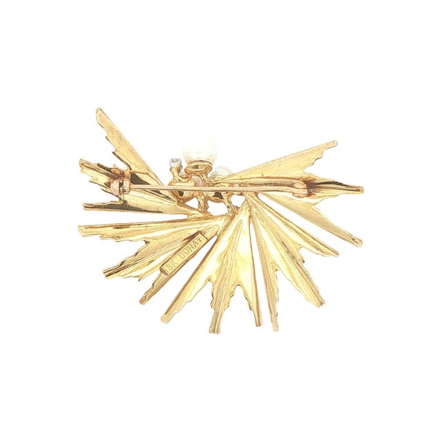 This brooch is crafted in 18k gold by Henry Dunay. The piece features a dynamic, starburst design with textured, radiating...