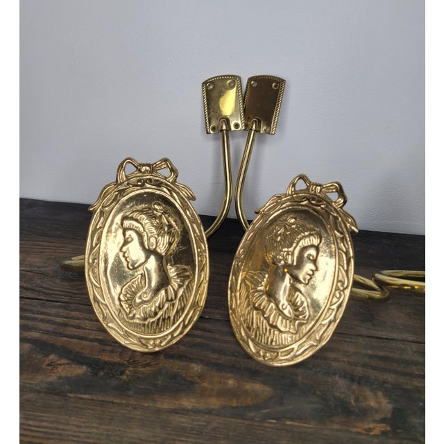 A stunning set of four (two pairs) solid brass curtain holdbacks featuring an elegant embossed profile of a Victorian-era...