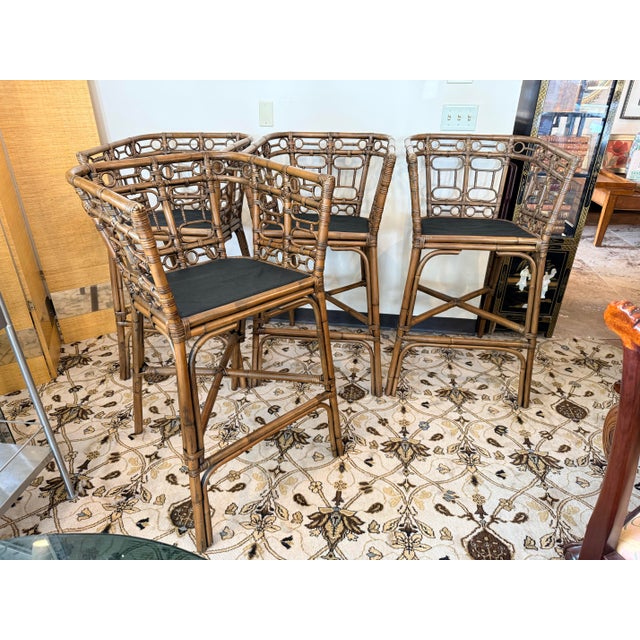 A stylish set of four vintage bamboo stools featuring an elegant open fretwork back, wrapped bamboo joints, and black...