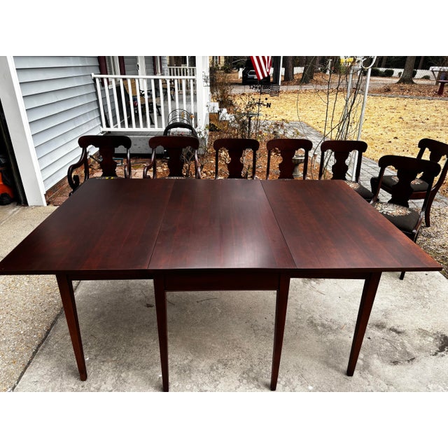 Solid mahogany drop leaf table with two arm chairs and five regular chairs. Seats have needle point embroidery. Built in...