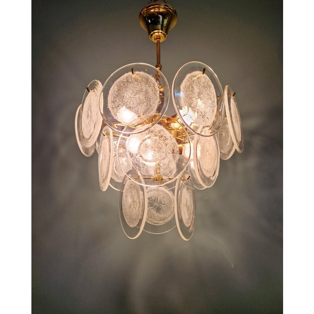 Brass chandelier with 18 Murano glass discs, Italy, 1970s. Each disc is clear with a frosted effect in the center and...