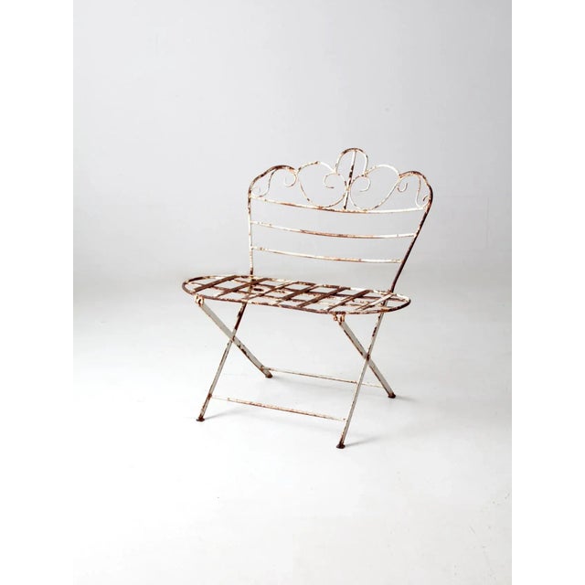 Antique metal garden bench featuring an Art Nouveau-inspired design with a graceful scrolling back rail and open grate...