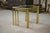 An elegant trio of nesting tables in polished brass, with a molded tubular frame reminiscent of bamboo and glass tops. The...