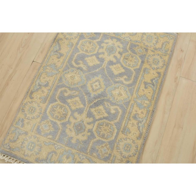 A traditional Oushak rug hand-knotted with an all-wool pile on a cotton foundation. This oriental rug features muted...