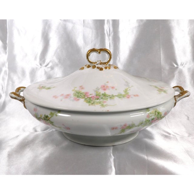 This is a white William Guerin Limoges covered oval casserole dish. It has a scattered pink and green floral design, some...