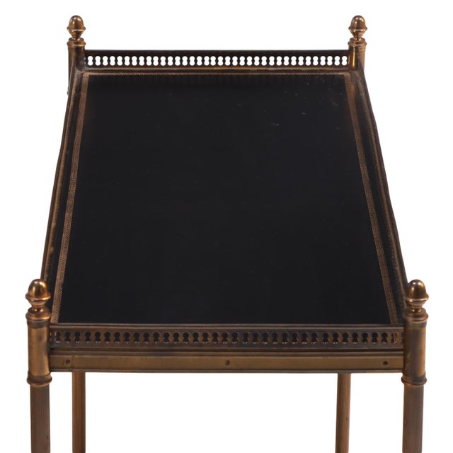 An elegant French two-tier occasional table in the manner of Maison Jansen, crafted with leather shelves framed in brass...