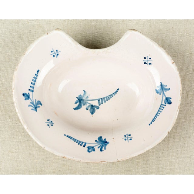 A 19th century French faience shaving bowl, hand-painted with blue flowers. Hairline crack.