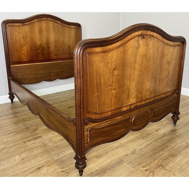 An elegant Antique French double bed crafted in walnut, featuring beautifully shaped head and footboards with warm natural...