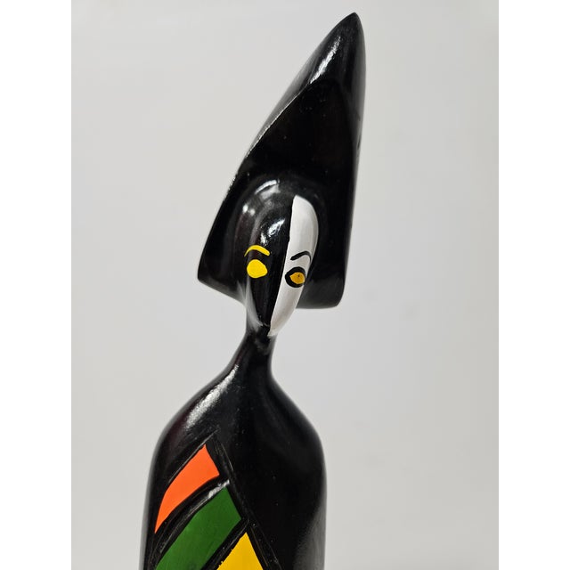 This whimsical wood sculpture of a person features a black lacquer base with vibrant colors added to the chest area of the...