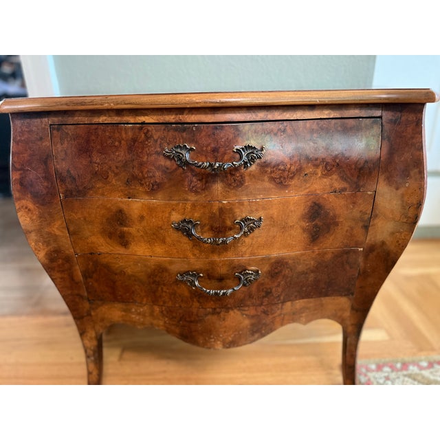 A gorgeous serpentine-front bombé commode in beautifully figured burl walnut. Three deep drawers glide smoothly, dressed...