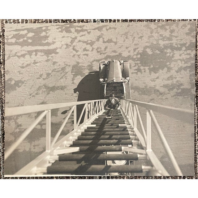 1930s sepia tone photograph of a man climbing the ladder of an old fire engine. Unsigned, with a blank back. Combined...