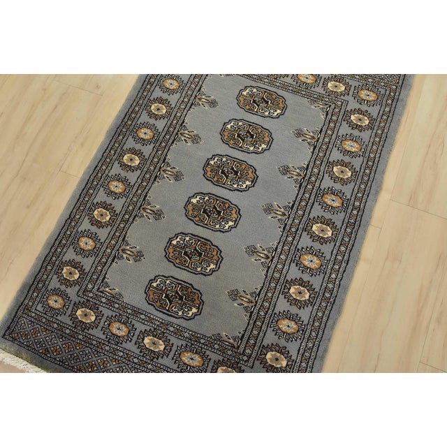 A tribal Bokhara rug hand-knotted with fine wool on a cotton foundation. This rug features a row of repeating medallions...