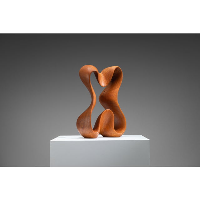 This vintage abstract sculpture is hand-carved from warm-toned teak wood and defined by a highly fluid, organic form. The...