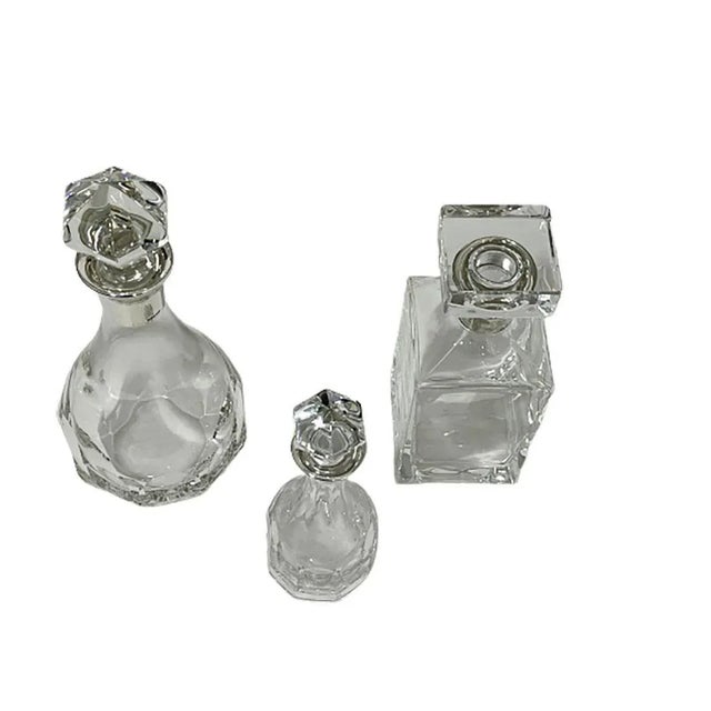 Three crystal with silver mounts decanters by Hermann Bauer, Germany. Three different decanters, in the shape of round,...