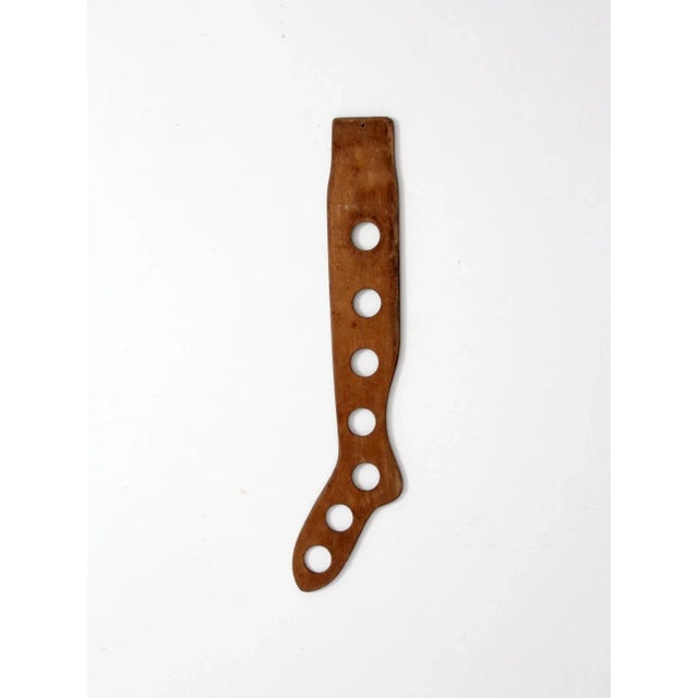 Striking antique wood sock stretcher with an elongated silhouette and seven circular cutouts. Warm aged wood and graphic...