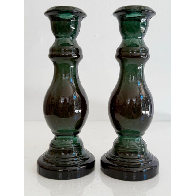 Pretty emerald green glass candlestick holders in a deep emerald green. Appear black in some light. Late 20th century....
