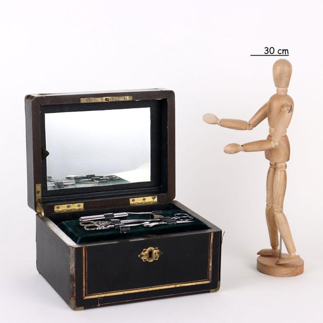 Ebony wood veneer sewing box with brass piping and inlay above the lid. Inside compartments and sewing tools. Under the...