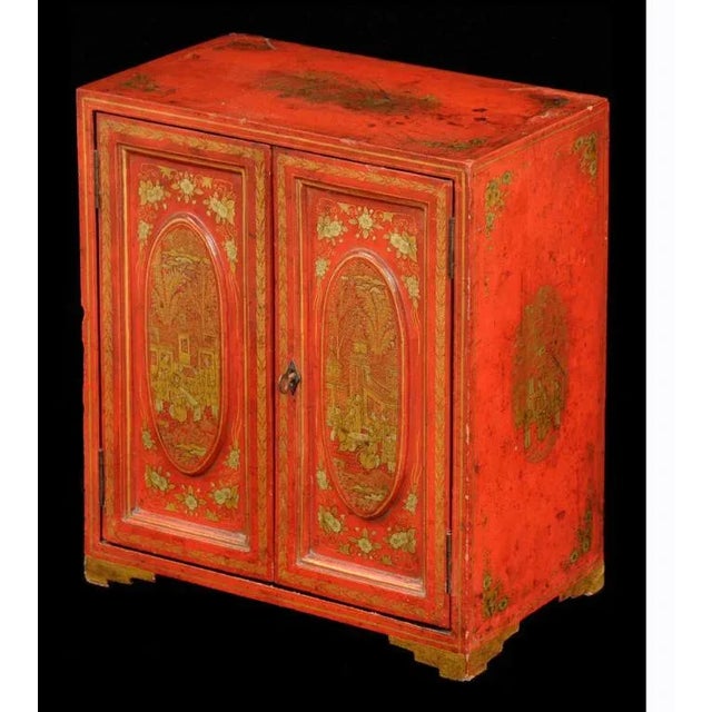 Chinese export miniature red lacquered table top cabinet with gilded decoration of figure having tea, pogodas, trees and...