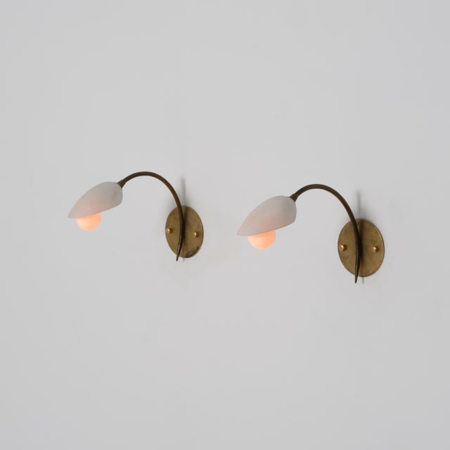 A refined pair of italian wall sconces from the 1950s, defined by a light and organic composition that combines brass and...